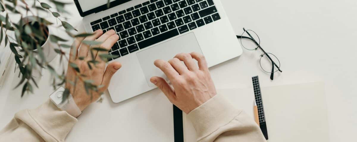 Free An overhead view of a person working on a laptop in a minimalist home office setting. Stock Photo