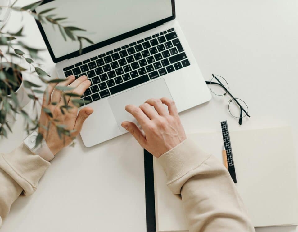 Free An overhead view of a person working on a laptop in a minimalist home office setting. Stock Photo