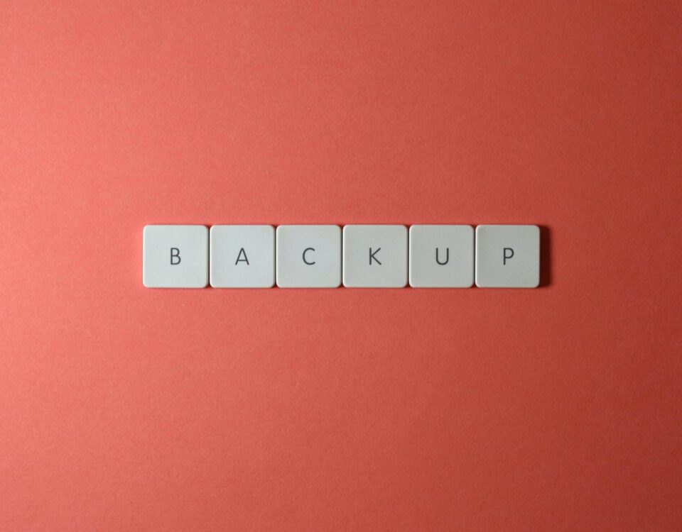 Free Close-up of keyboard keys spelling 'BACKUP' placed on a coral-colored surface. Stock Photo